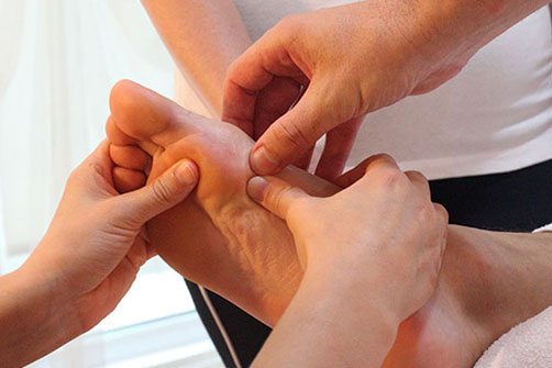 Profesorul indică puncte reflexe pe talpa cursantului în timpul cursului de masaj reflexogen, la Școala Perfect Euforic Masaj din București